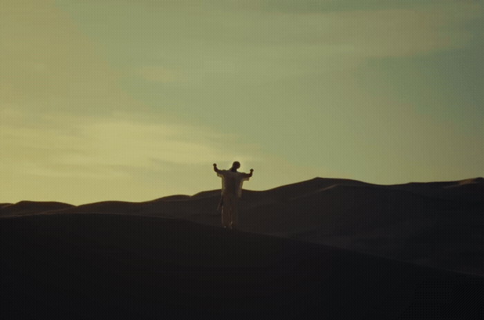 a man standing on top of a sandy hill