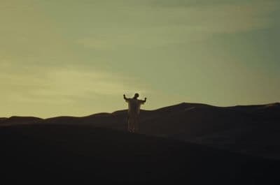 a man standing on top of a sandy hill