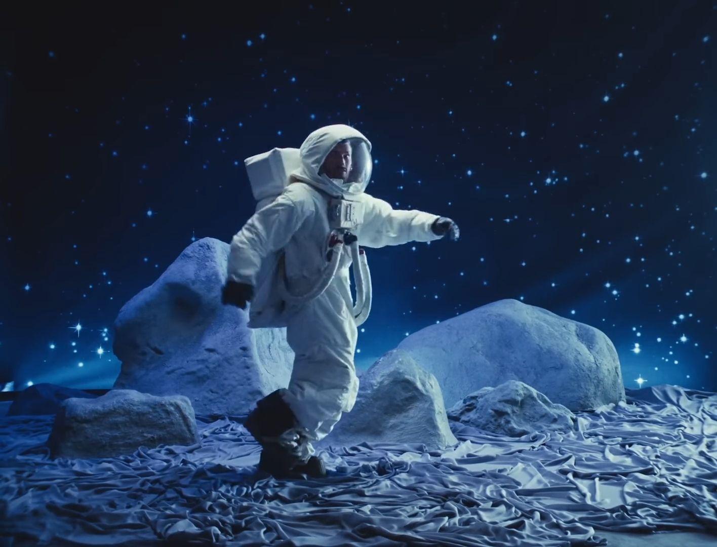 a man in a space suit standing on a rocky surface