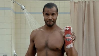 a shirtless man holding a bottle of soap in a bathroom