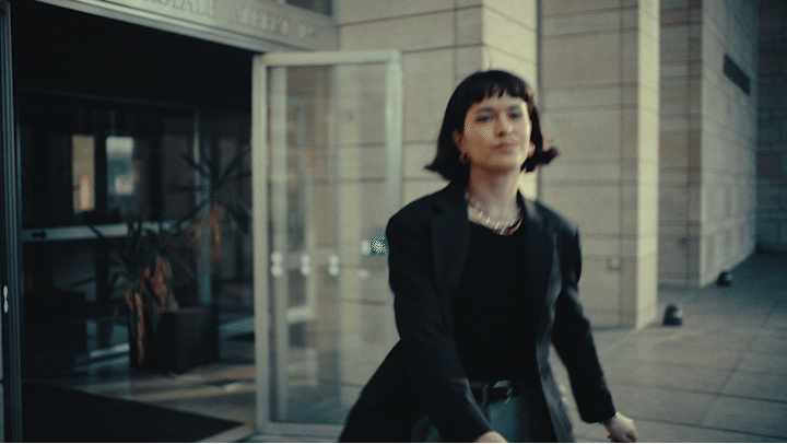 a woman walking down a street next to a tall building