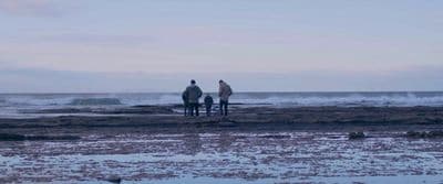 a couple of people standing on top of a beach
