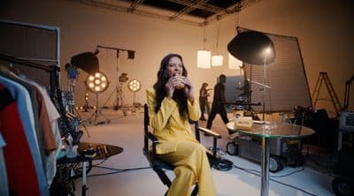 a woman sitting in a chair in front of a camera