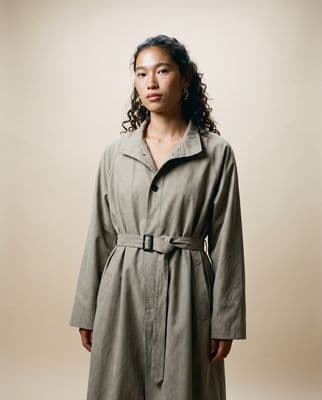 a woman in a trench coat standing in front of a wall