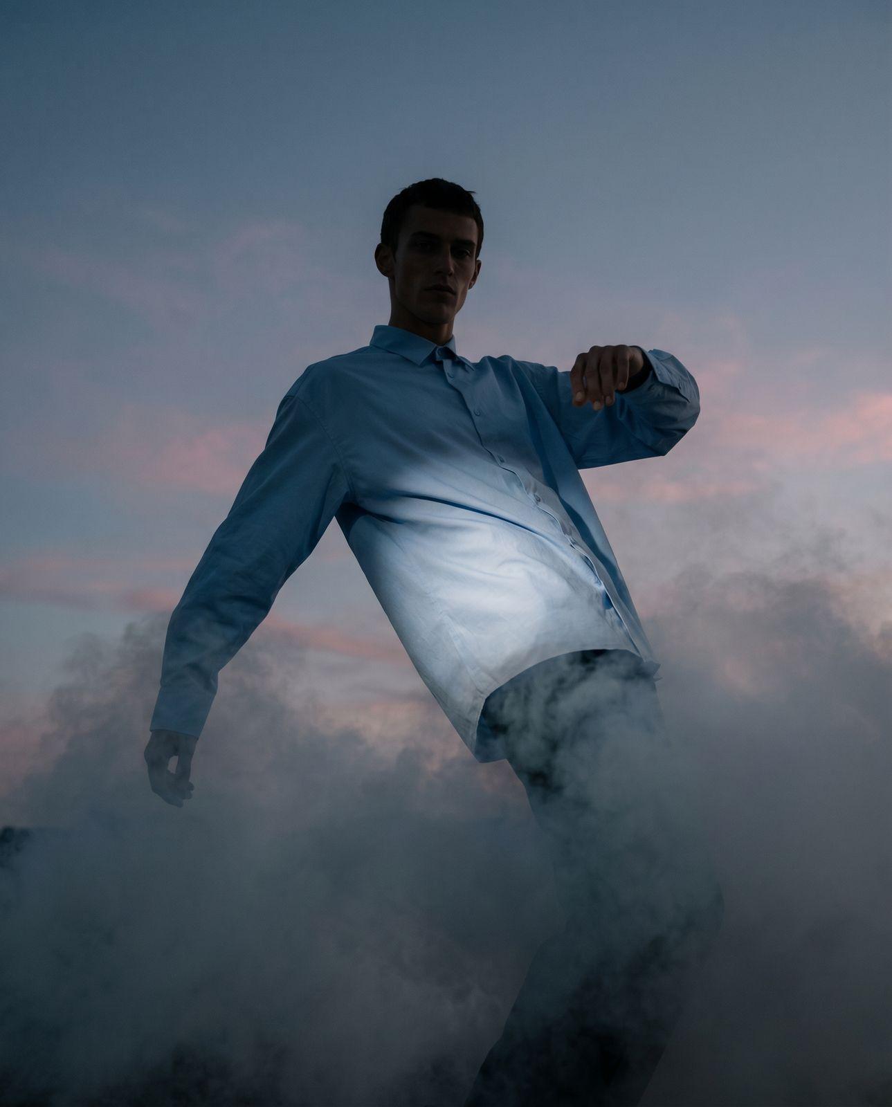 a man in a blue shirt is standing in the clouds