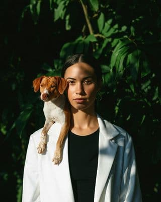 a woman in a white jacket holding a brown and white dog