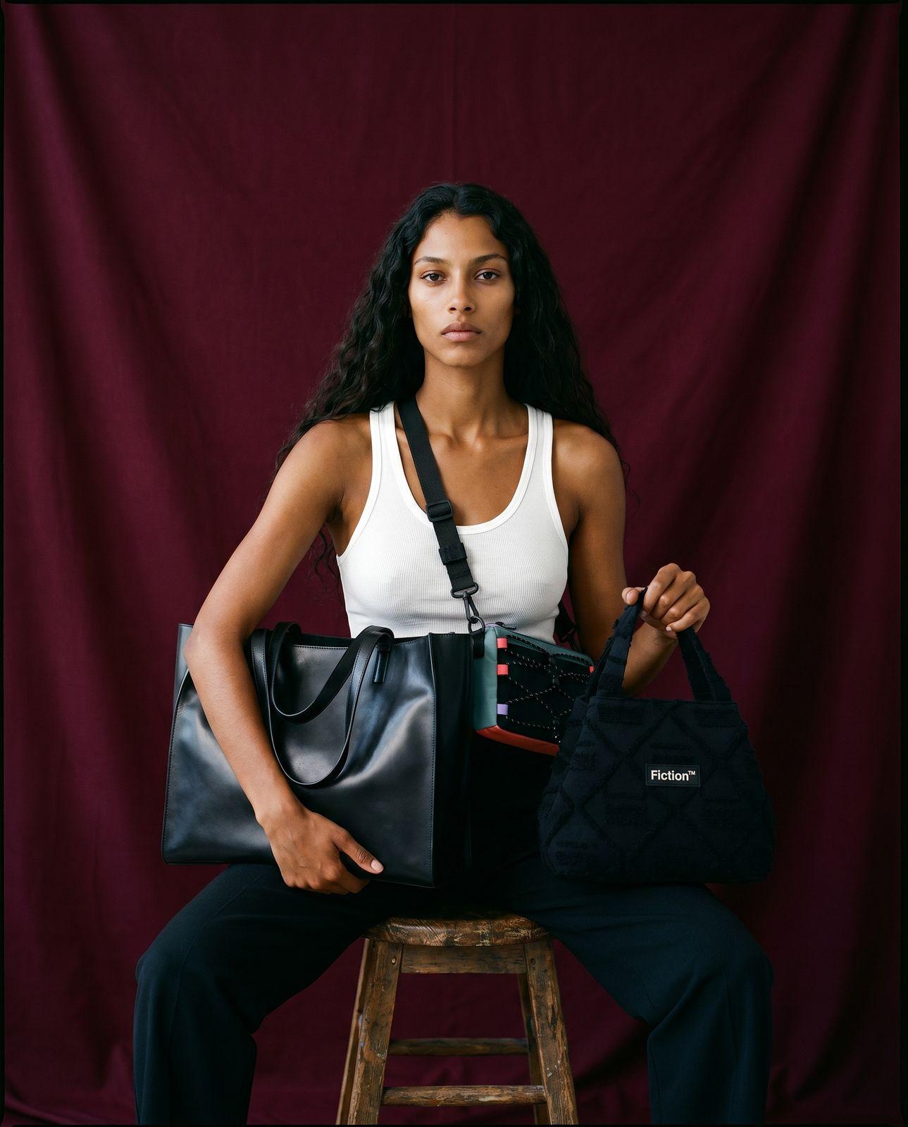 a woman sitting on a stool holding two bags