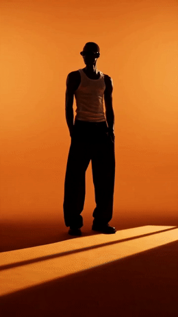 a man standing in the shadows of an orange wall