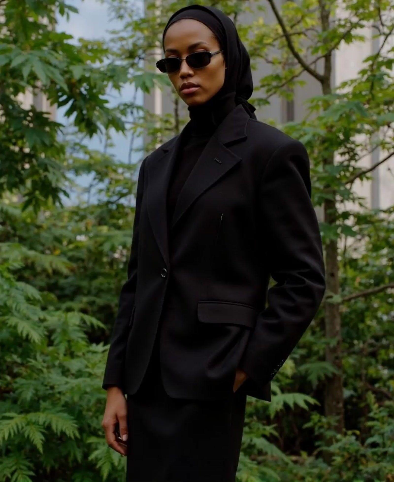 a woman in a black suit and sunglasses