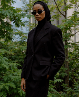 a woman in a black suit and sunglasses
