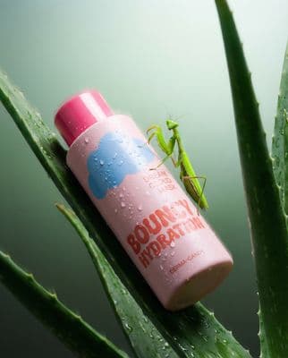 a green insect sitting on top of a pink bottle
