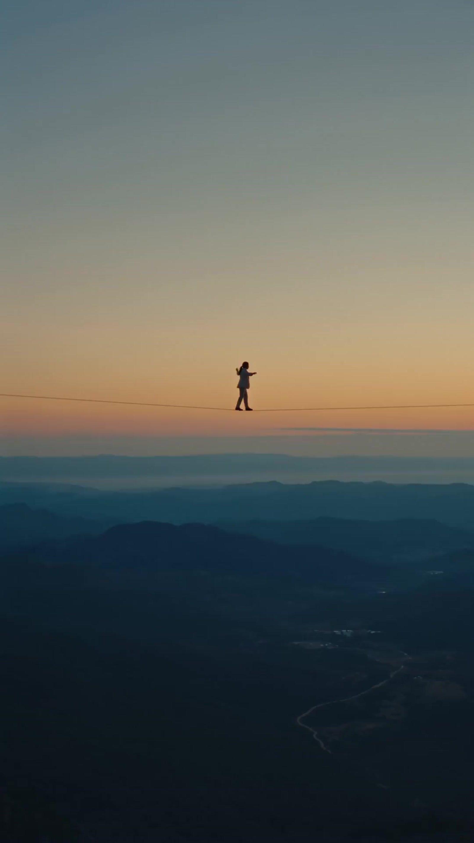 a person standing on a wire above a valley