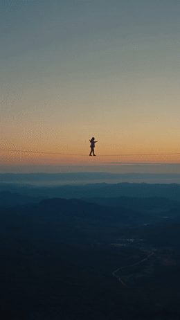 a person standing on a wire above a valley