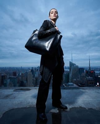 a woman holding a large black bag on top of a building