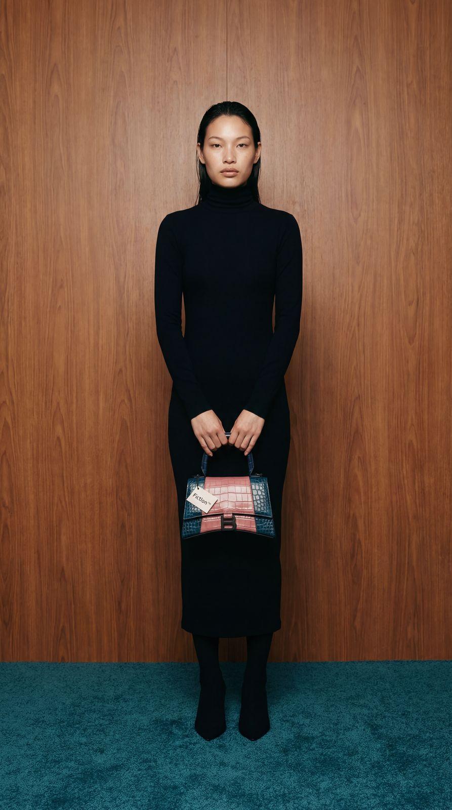 a woman in a black dress holding a purse