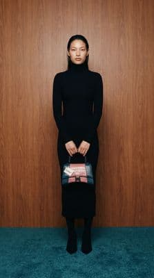 a woman in a black dress holding a purse