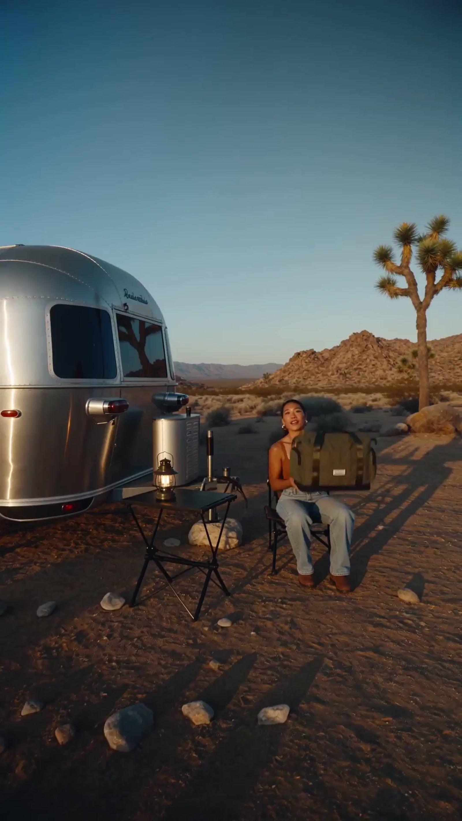 a man sitting in a chair next to a silver trailer