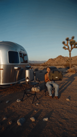 a man sitting in a chair next to a silver trailer