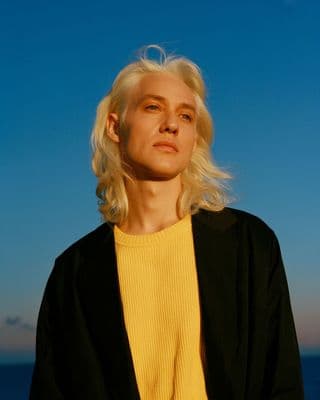 a woman with blonde hair standing in front of the ocean