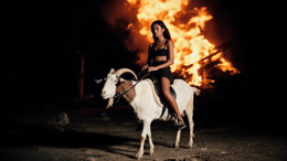 a woman riding on the back of a white goat