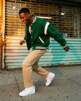 a man in a green jacket is walking down the street