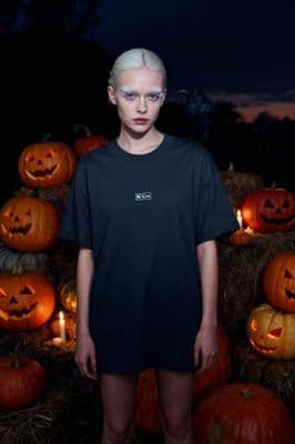 a woman standing in front of a pile of pumpkins