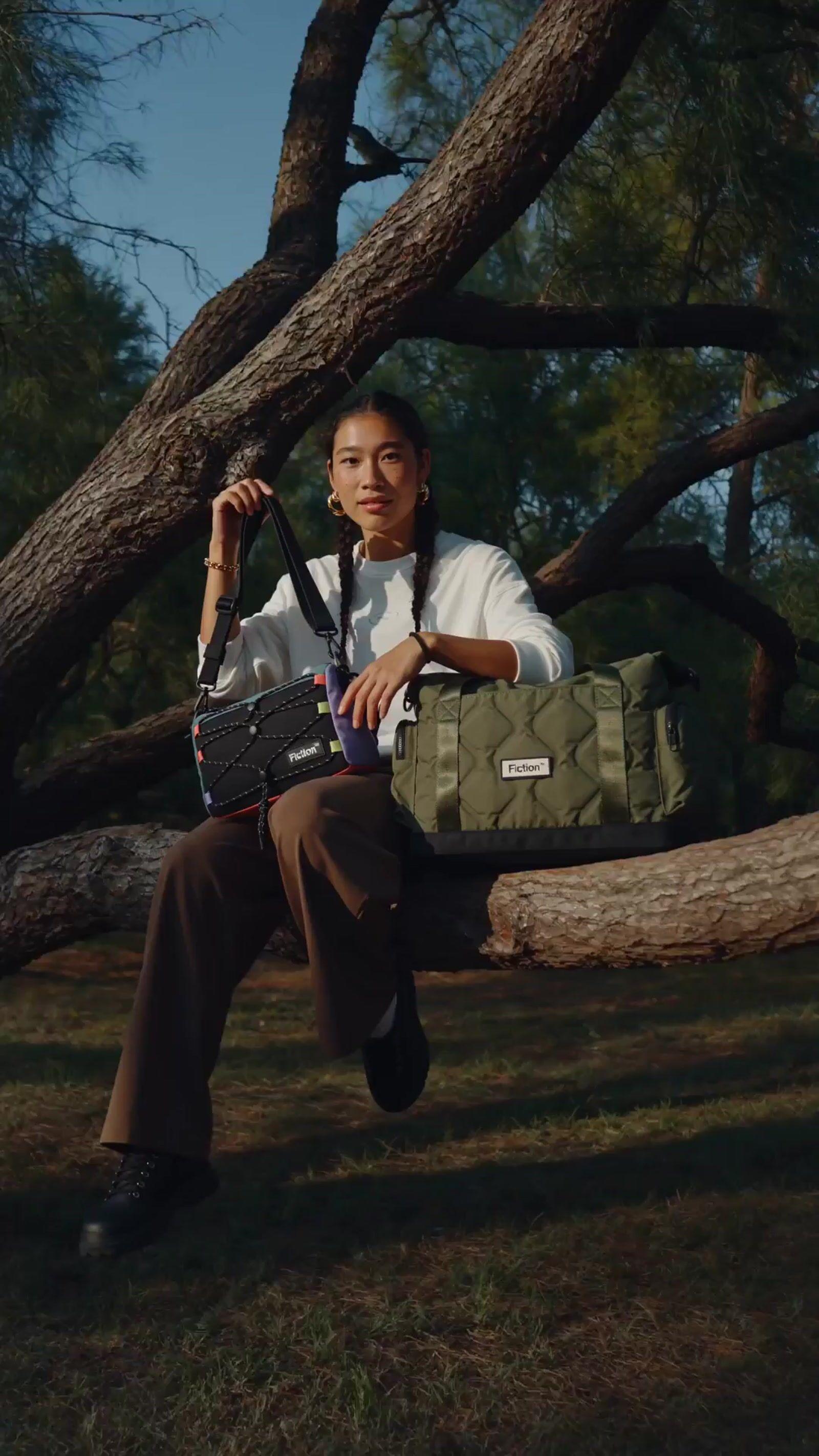 a woman sitting on a tree branch holding a camera