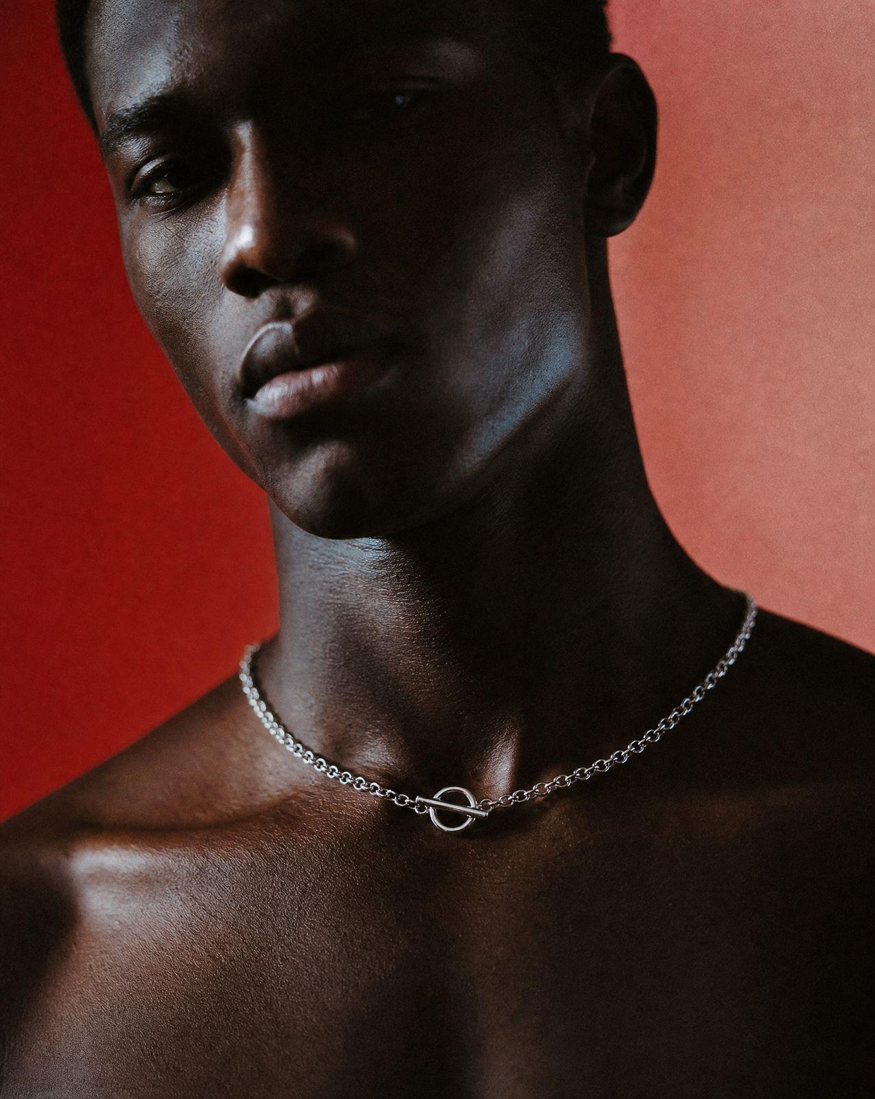 a shirtless man with a chain around his neck