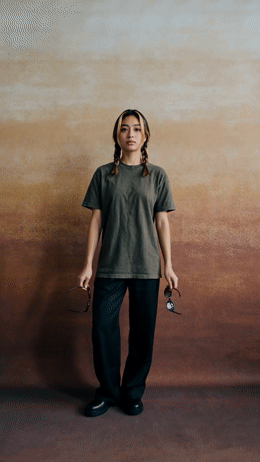 a woman standing in front of a brown wall