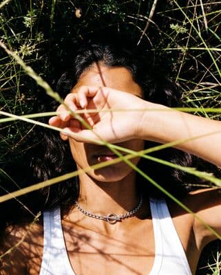 a woman in a tank top laying in the grass