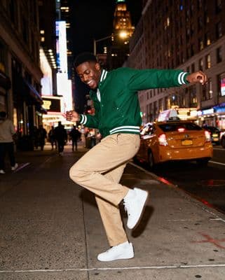 a man in a green jacket doing a trick on a skateboard