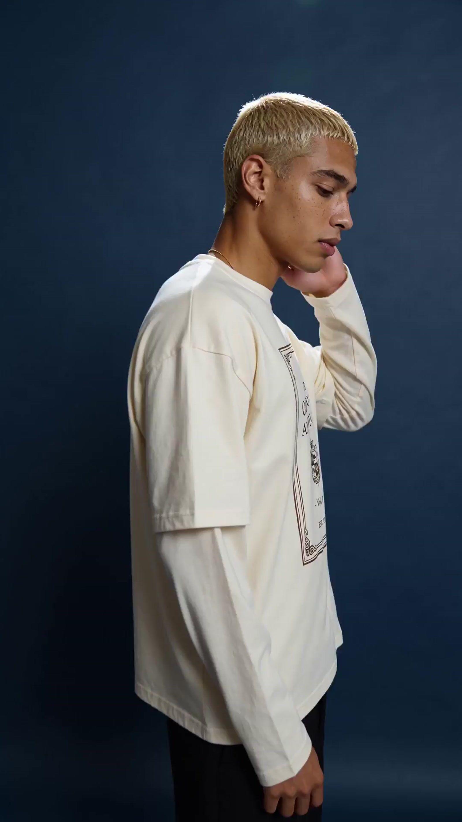 a man in a white shirt is holding his hand to his face