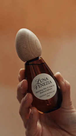 a hand holding a bottle of soap with a wooden stopper