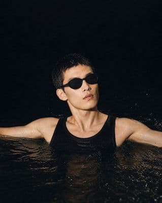 a man in a black tank top and sunglasses in the water