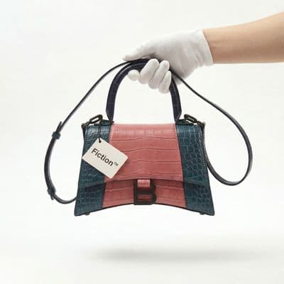 a hand holding a small purse with a tag on it