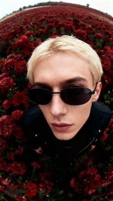 a man wearing sunglasses is standing in front of flowers
