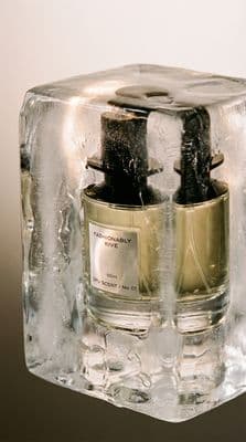 a couple of bottles of perfume sitting on top of a block of ice