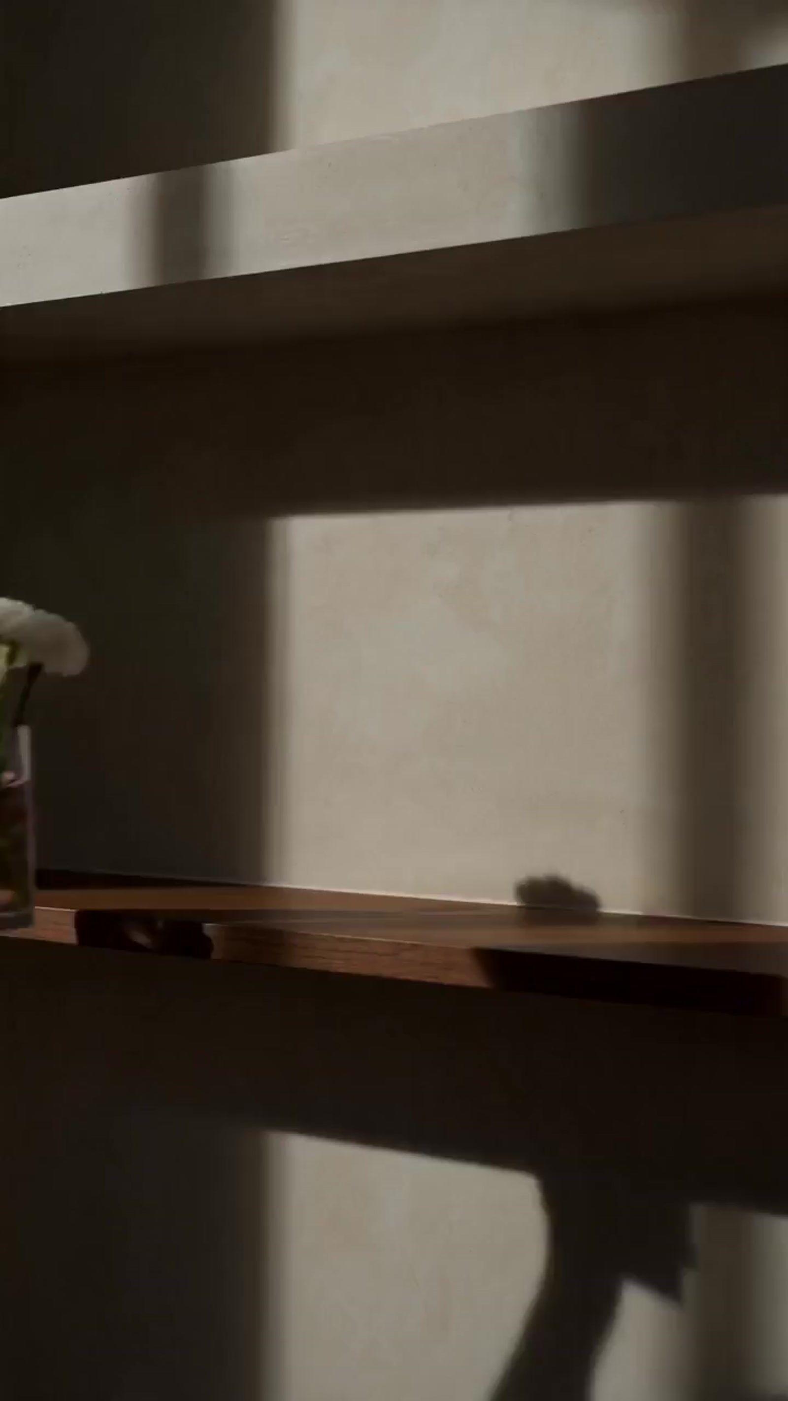 the shadow of a person's hand on a shelf