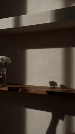 the shadow of a person's hand on a shelf