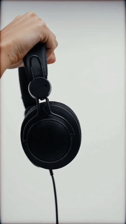 a hand holding a pair of black headphones
