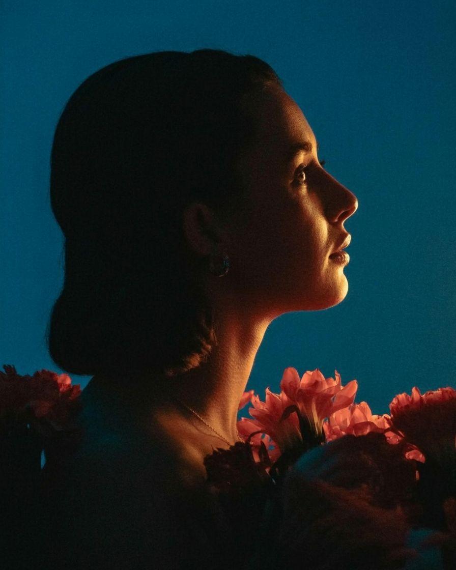 a woman with flowers in her hair looking off into the distance