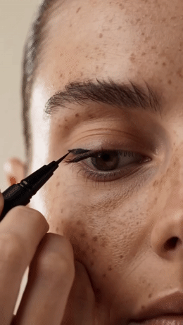 a close up of a person putting a mascara on their eye