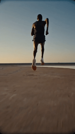 a man running across a sandy beach under a blue sky