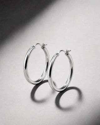 a pair of silver hoop earrings on a white surface