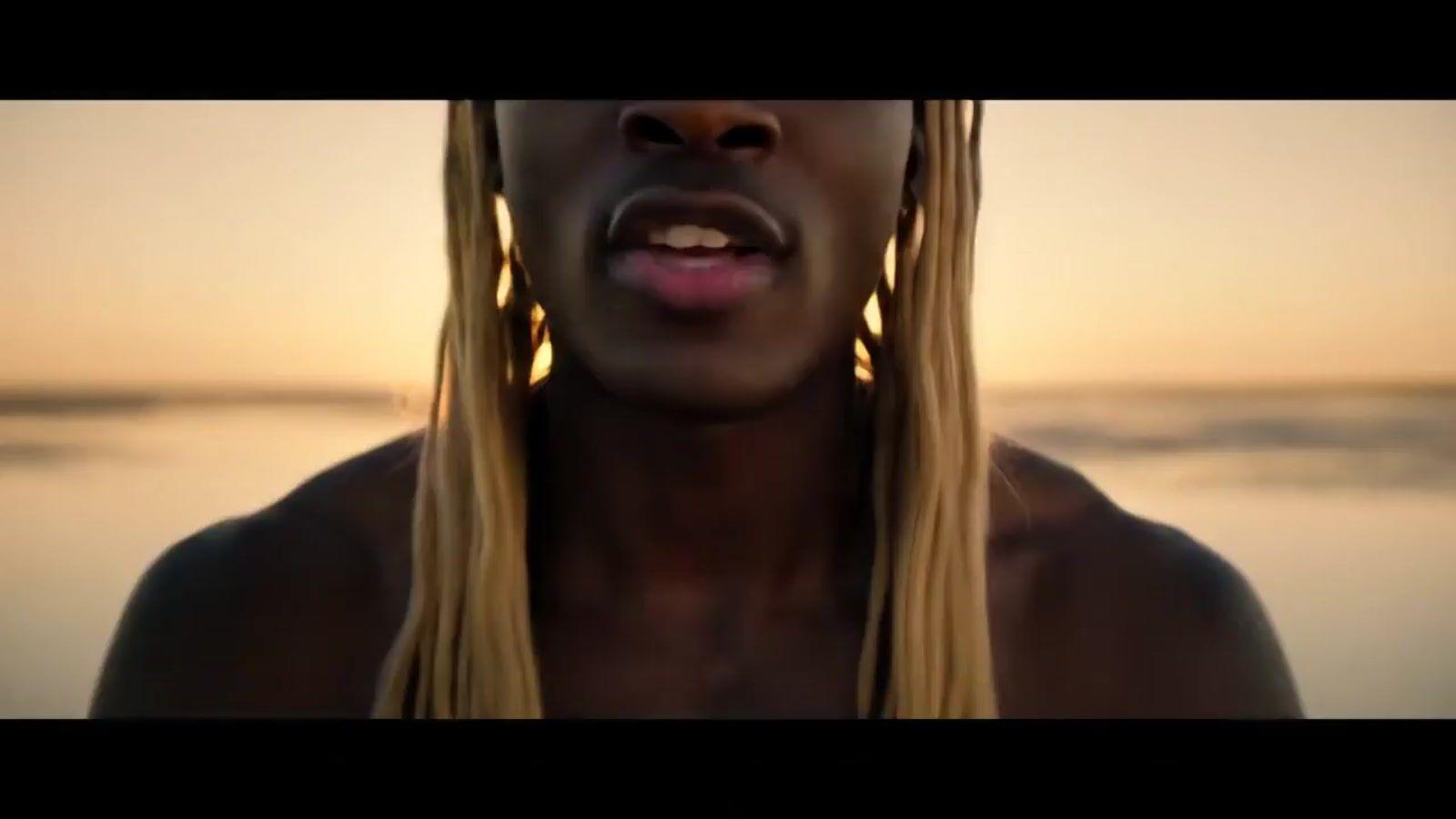 a woman with long blonde hair standing in front of a body of water