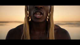a woman with long blonde hair standing in front of a body of water