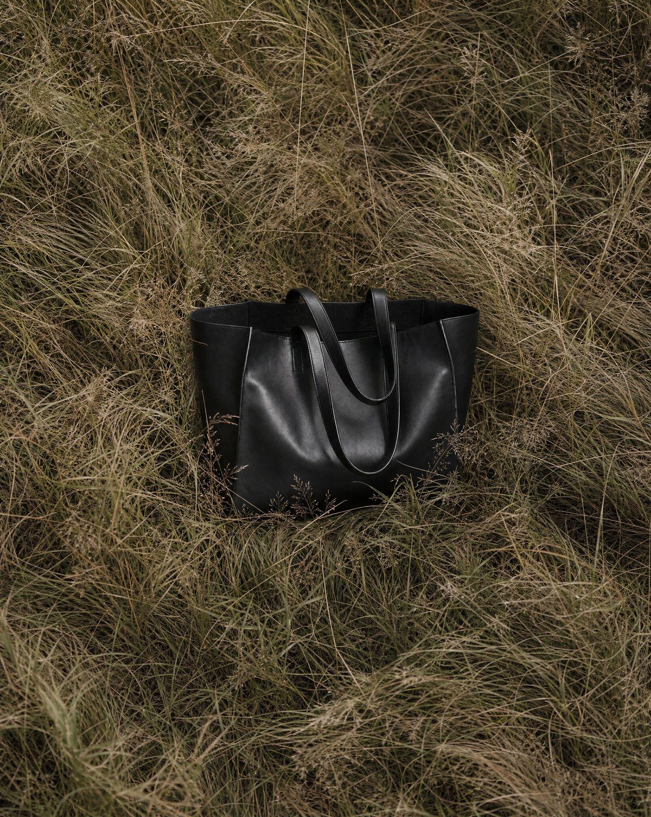 a black bag laying in a field of grass