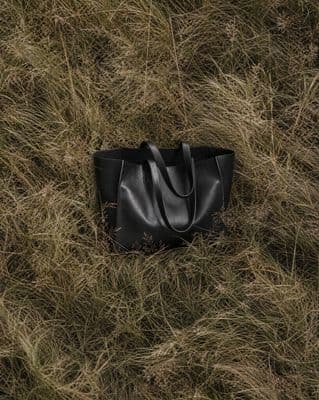 a black bag laying in a field of grass
