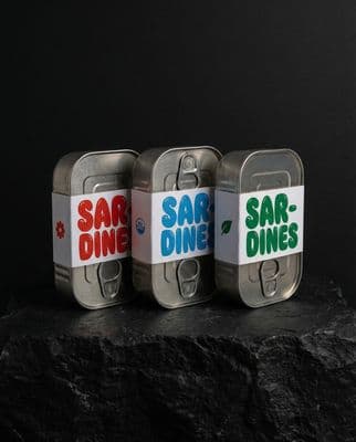 three tins of food sitting on top of a rock