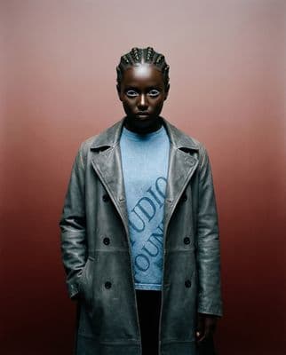 a man wearing a blue shirt and a gray coat